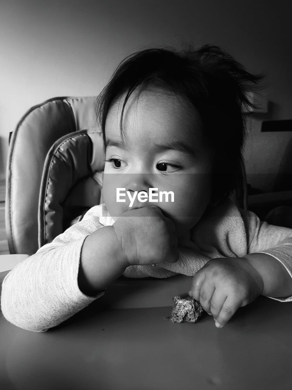 Close-up of cute baby girl sitting on chair at home