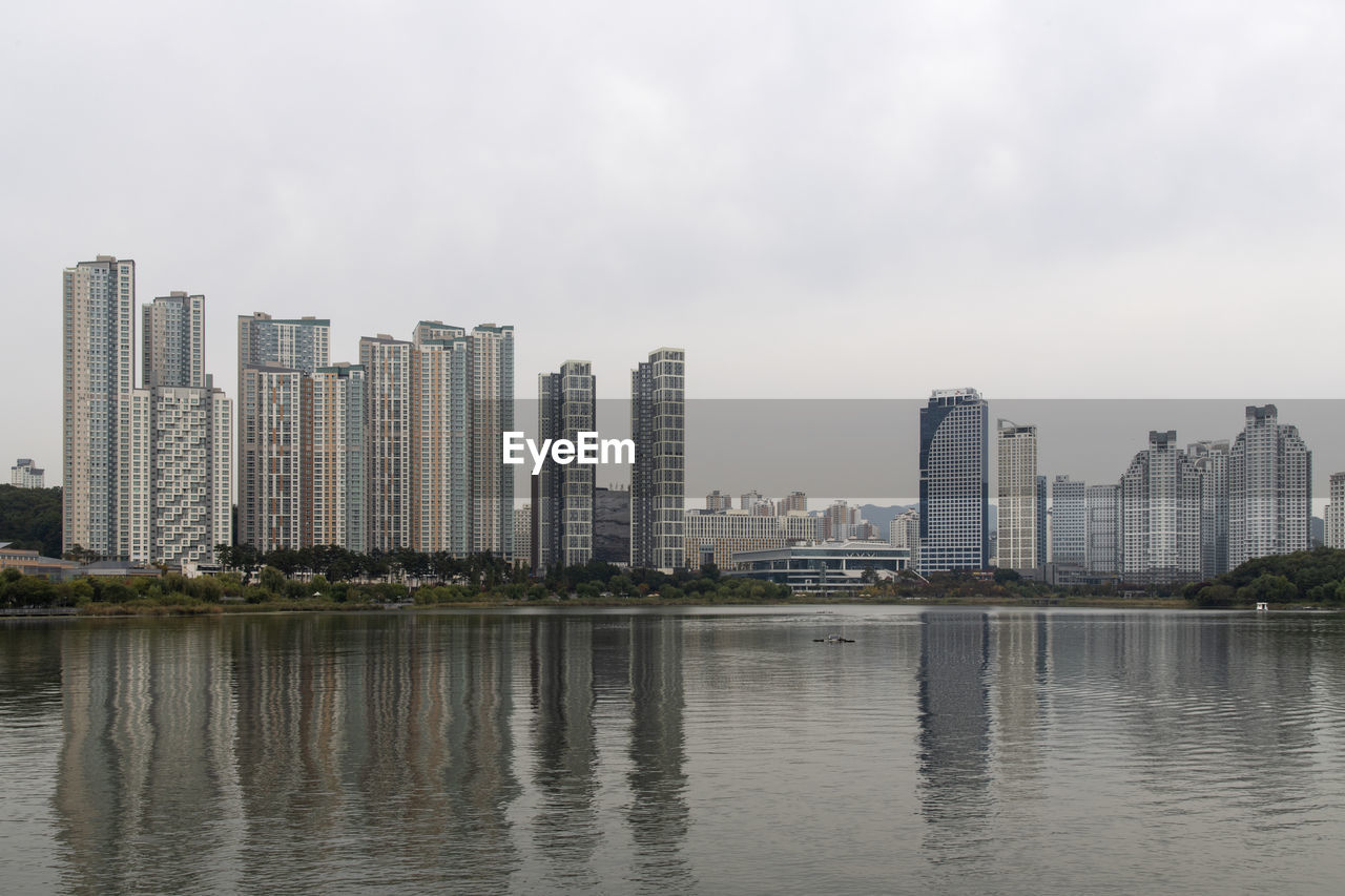 Buildings by river against sky in city