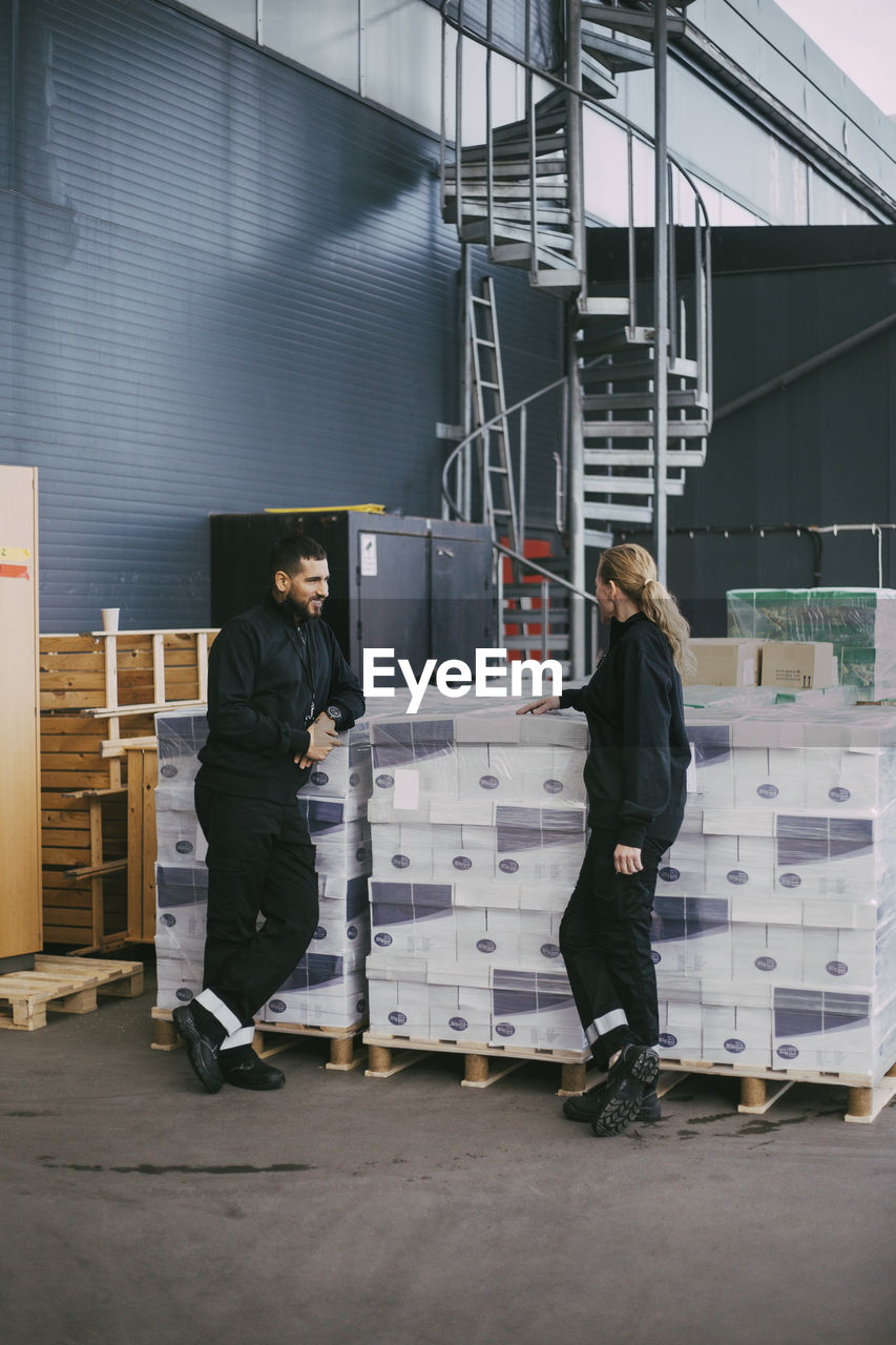 Female and male professional standing by packages at warehouse