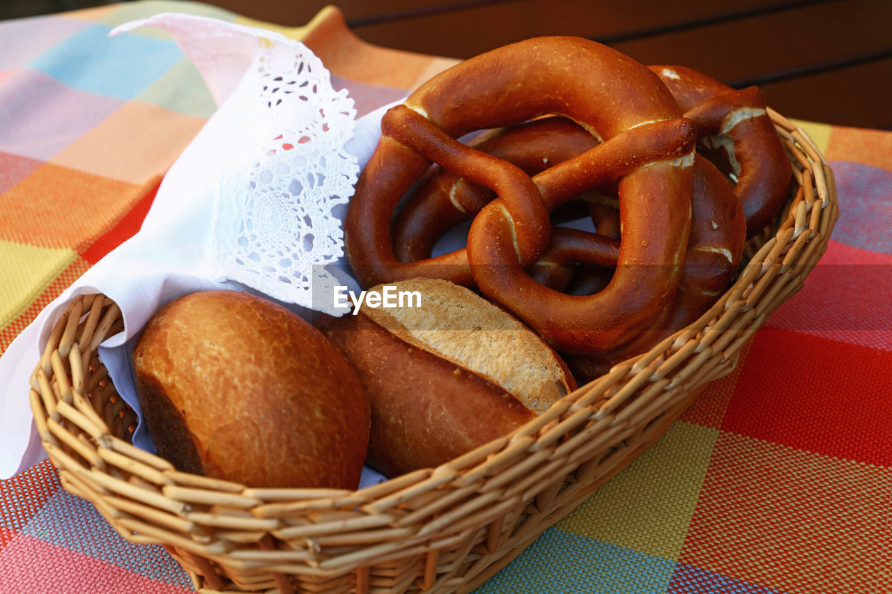 Close-up of pretzel and bread in wicker basket on tablecloth