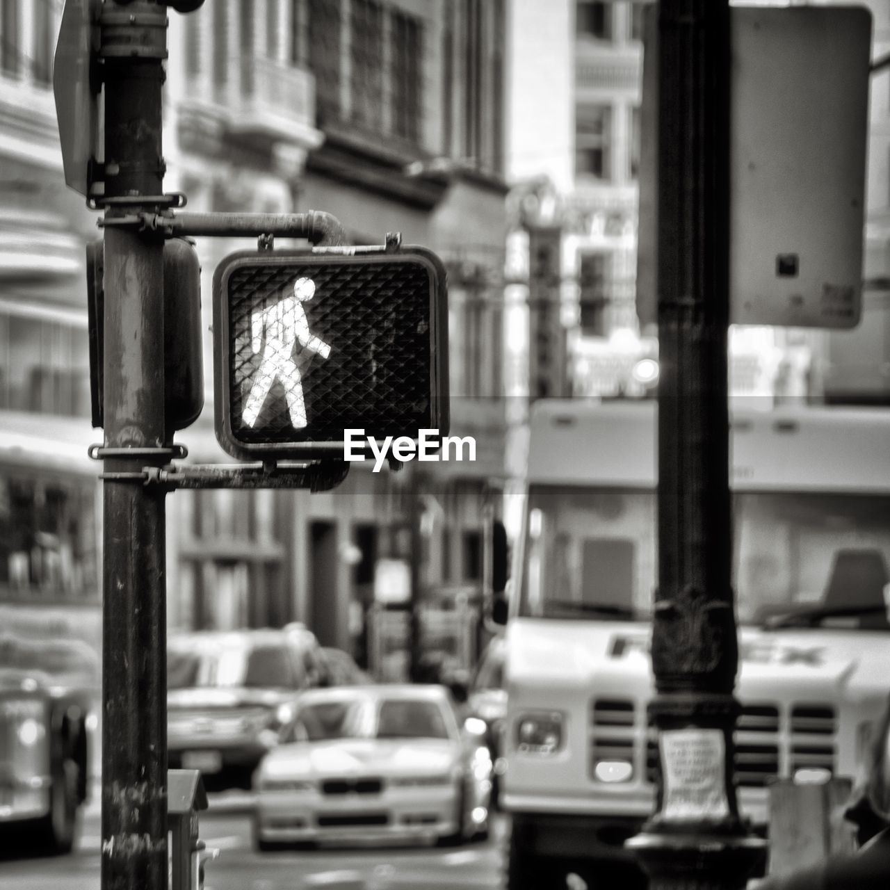 Pedestrian crossing sign against vehicles on street in city