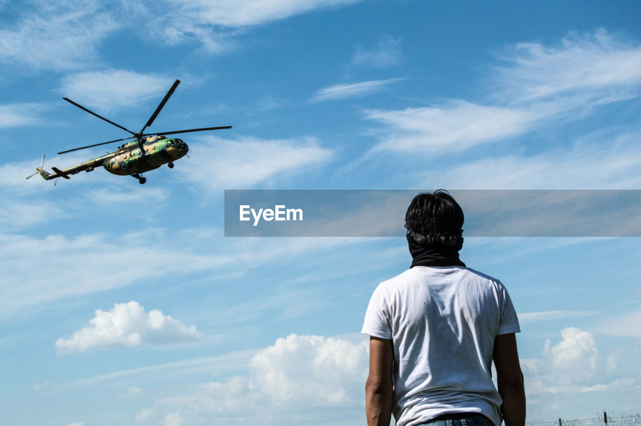 Rear view of man looking at helicopter