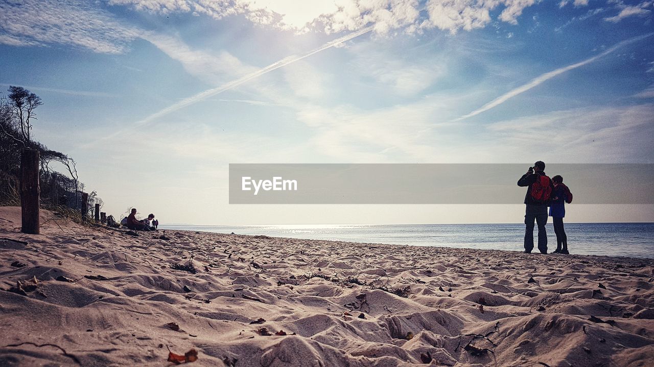 Men standing on beach against sky