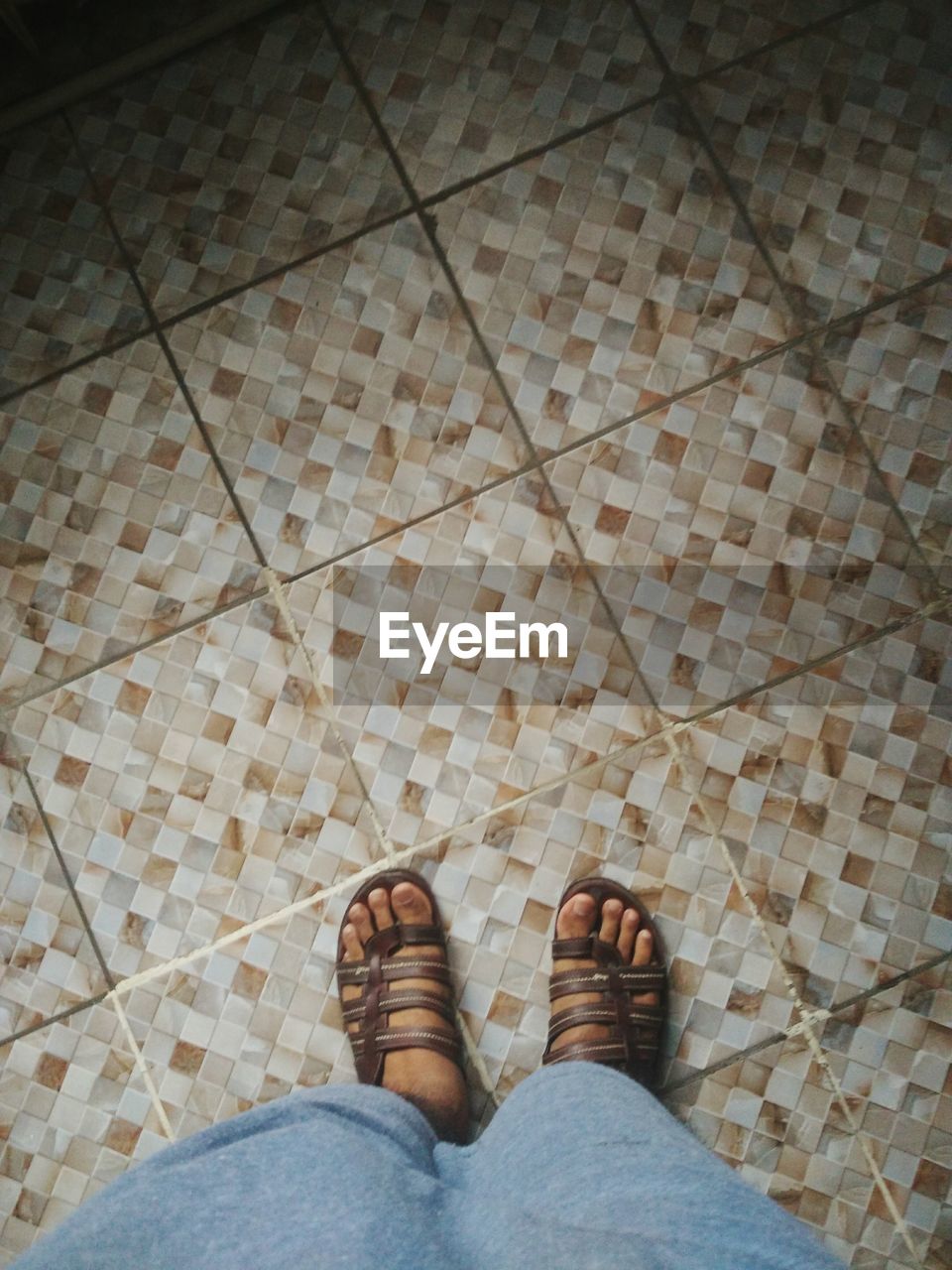 LOW SECTION VIEW OF MAN STANDING ON TILED FLOOR