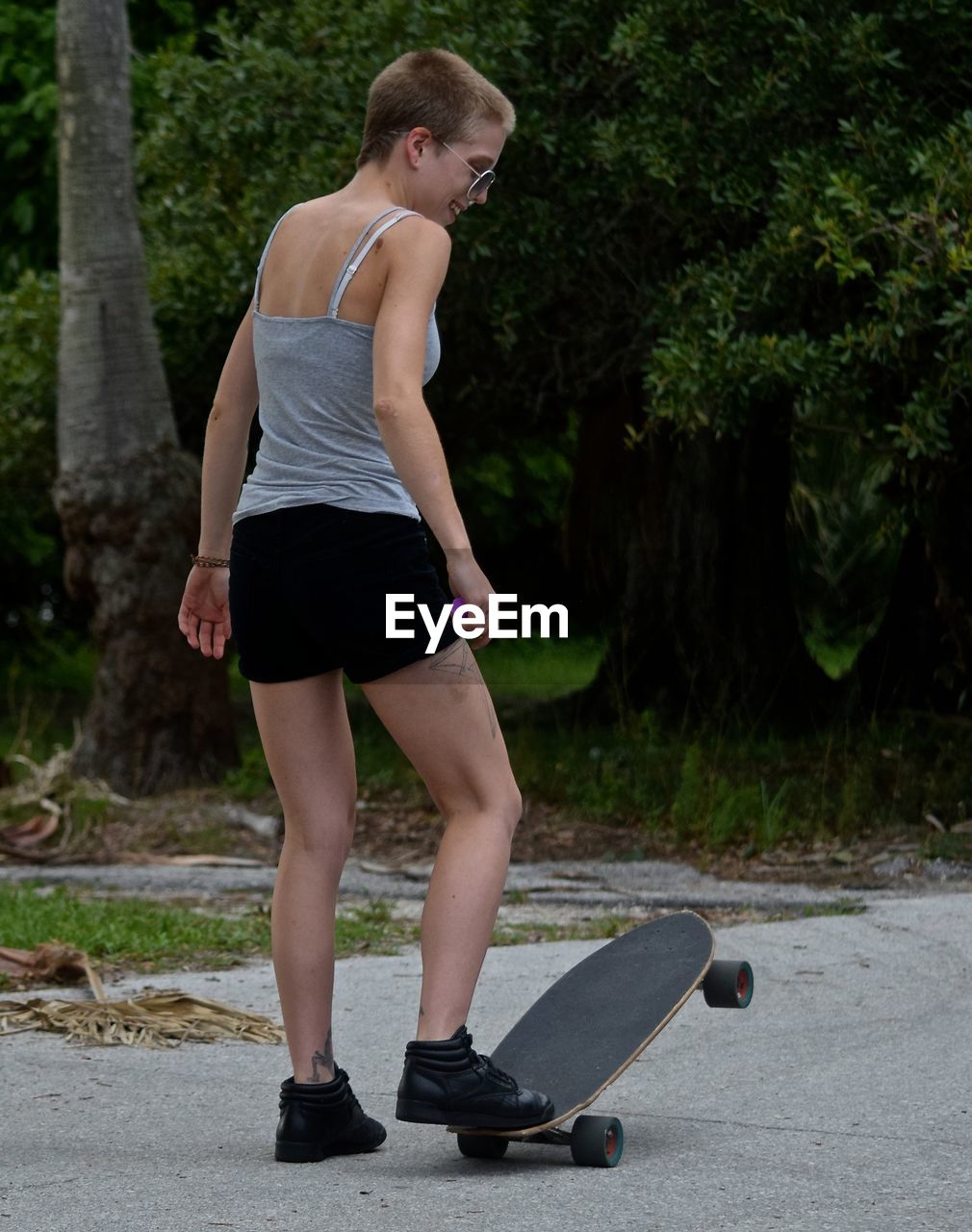 Rear view of woman with skateboard standing on road