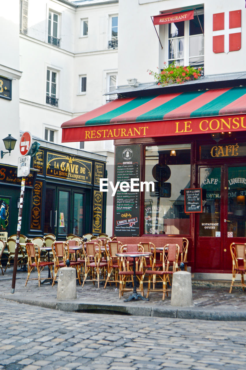 CHAIRS AND TABLES AT SIDEWALK CAFE AGAINST BUILDING