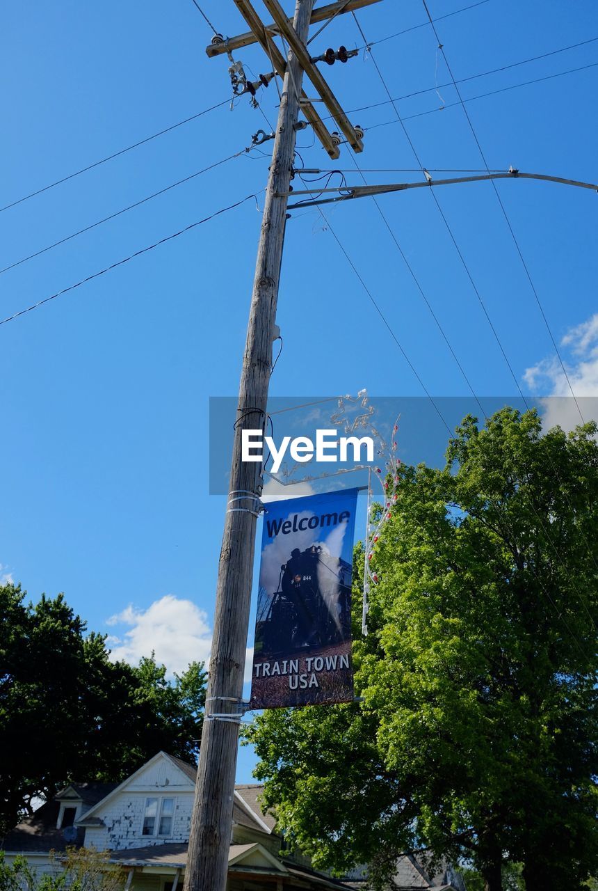 LOW ANGLE VIEW OF ROAD SIGN AGAINST TREES