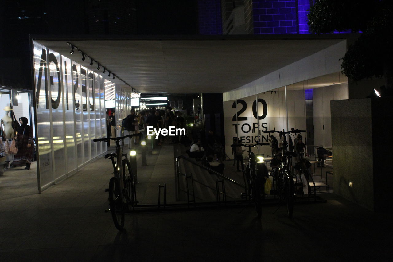 ILLUMINATED SIGN ON STREET BY BUILDINGS AT NIGHT