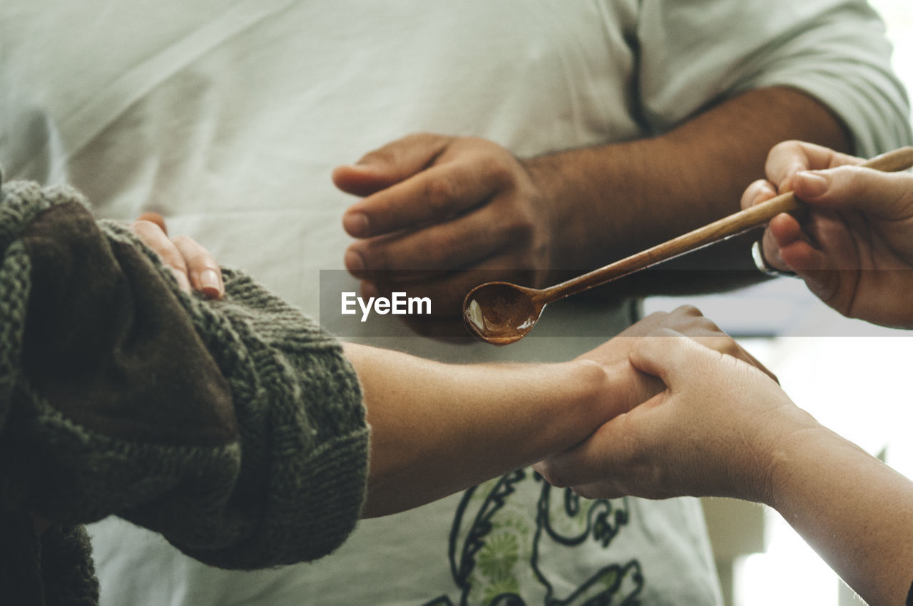 Cropped image of person pouring liquid on woman hand