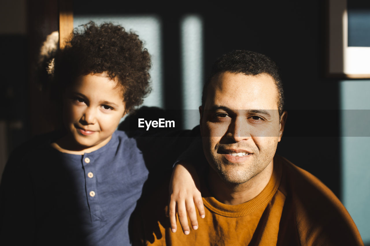 Portrait of father and son with sunlight falling on face at home