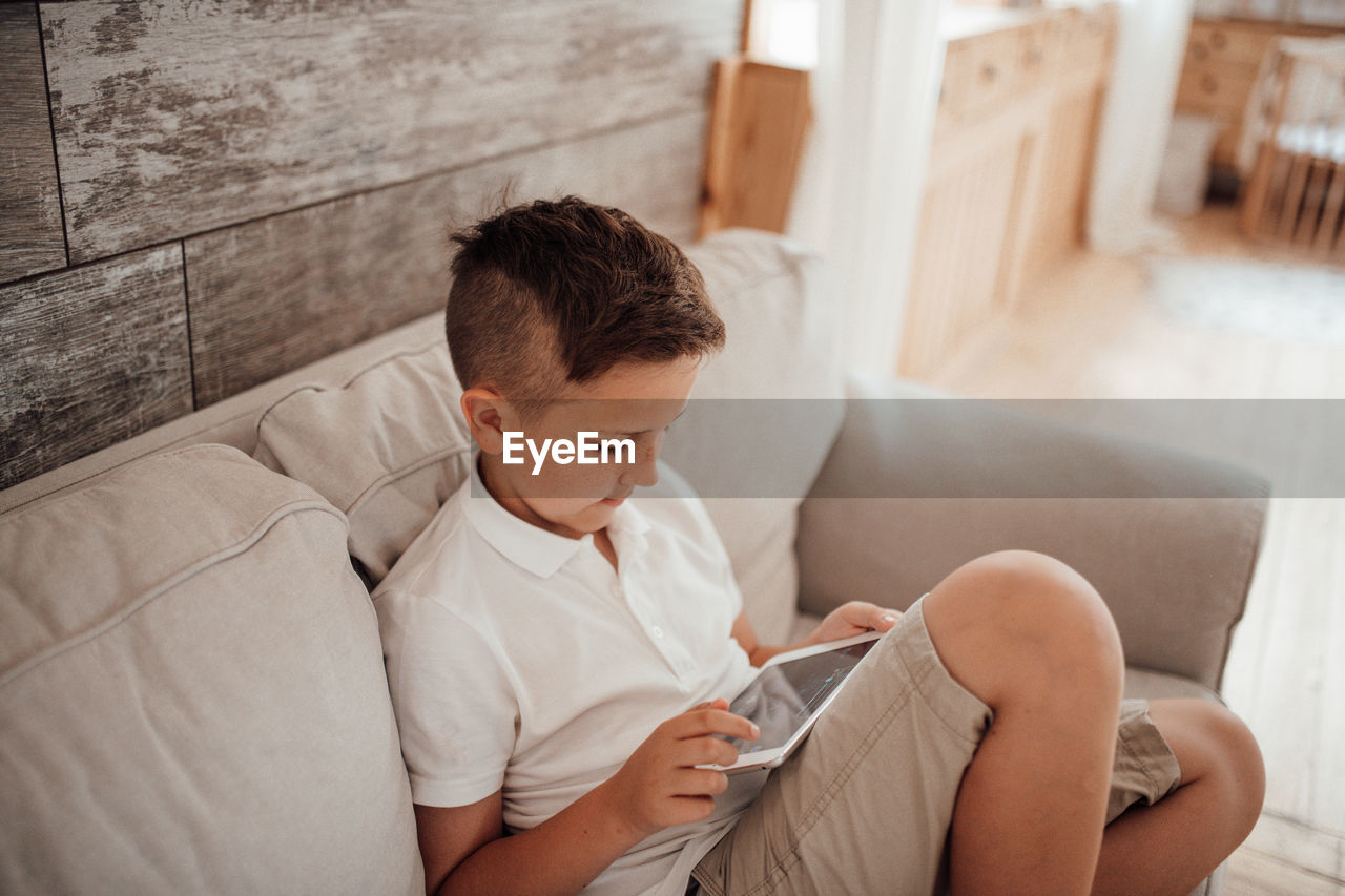 Boy sitting on sofa at home