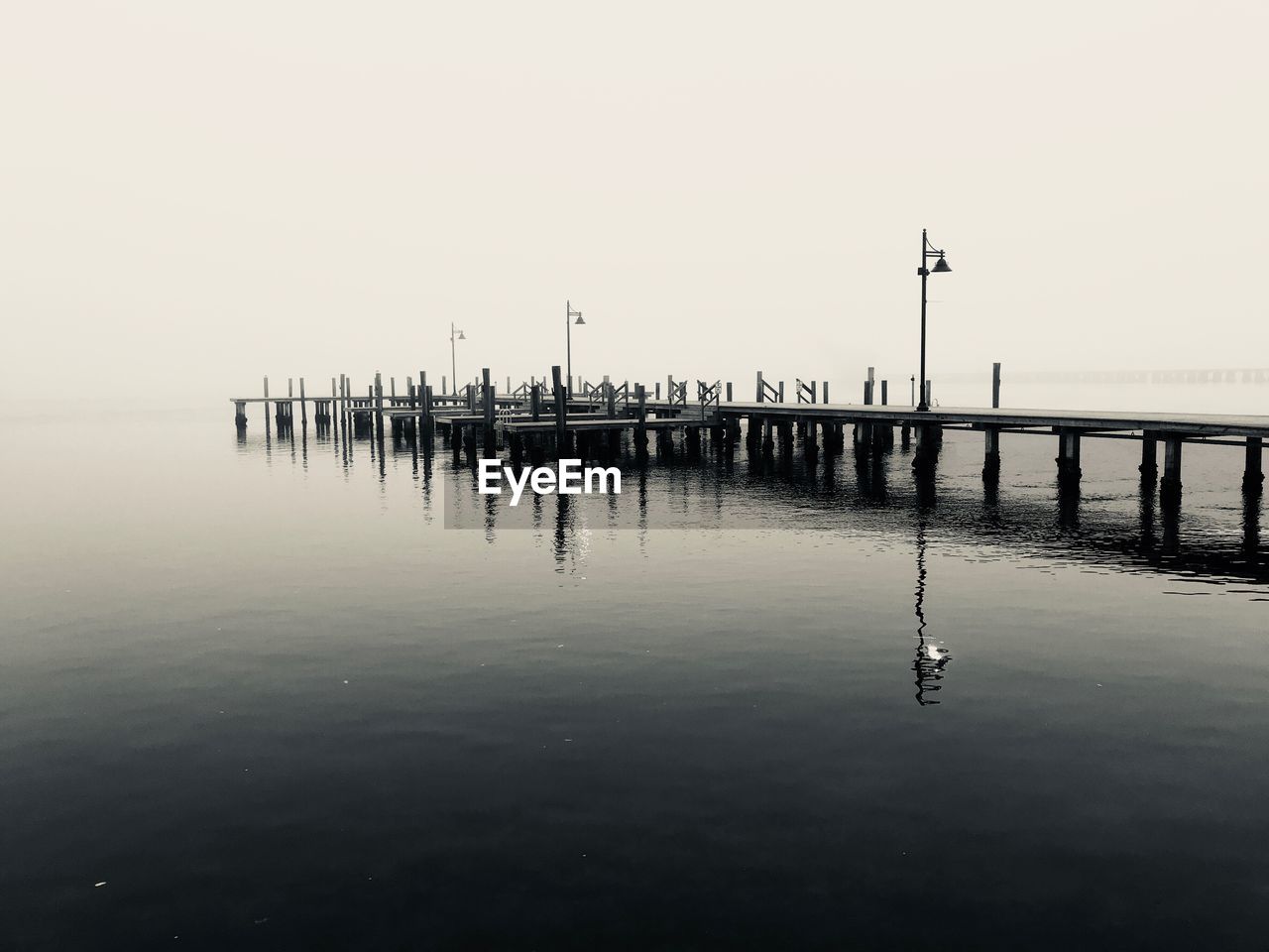 WOODEN POSTS ON PIER AGAINST SEA