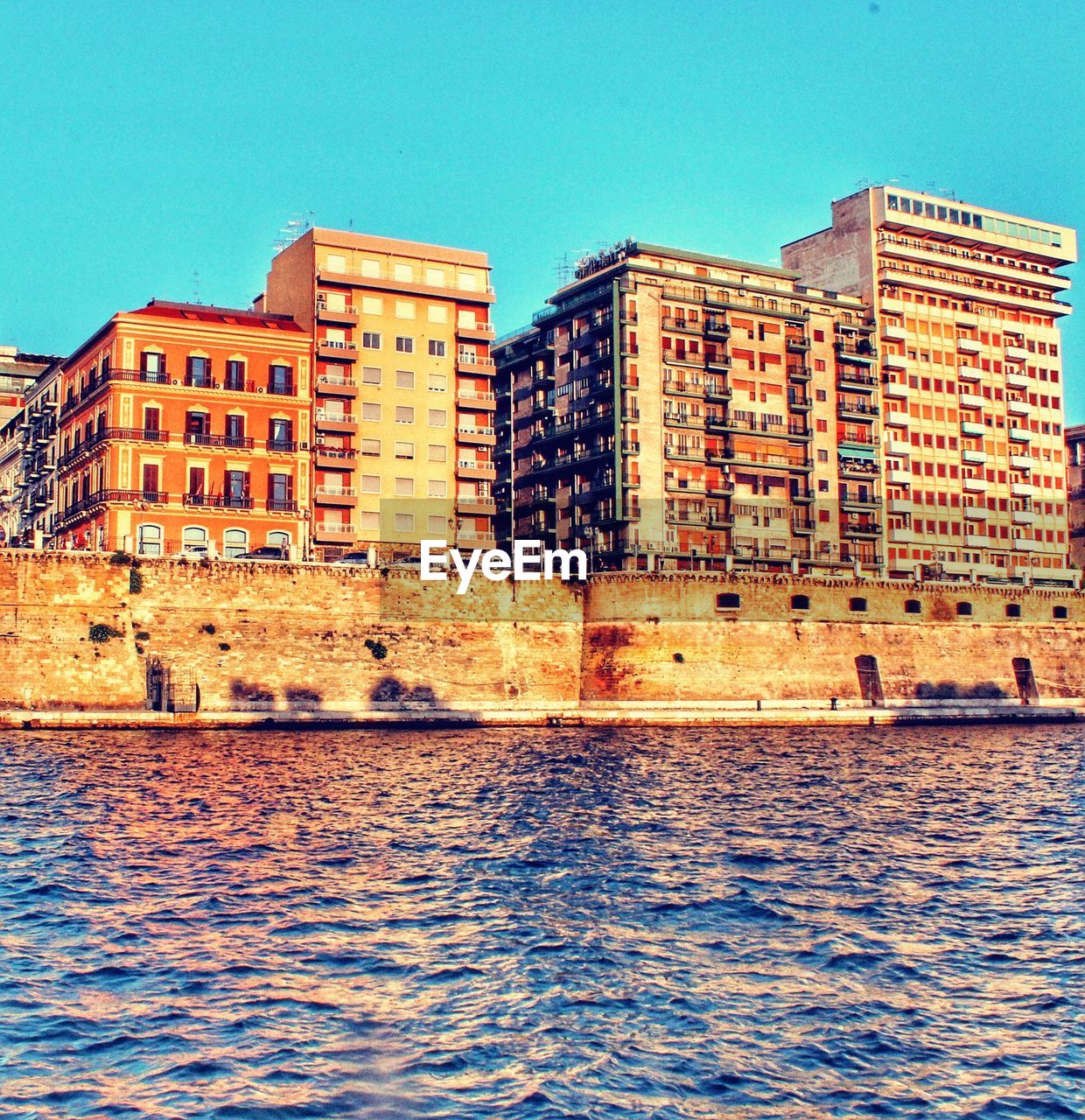 River by buildings against clear blue sky