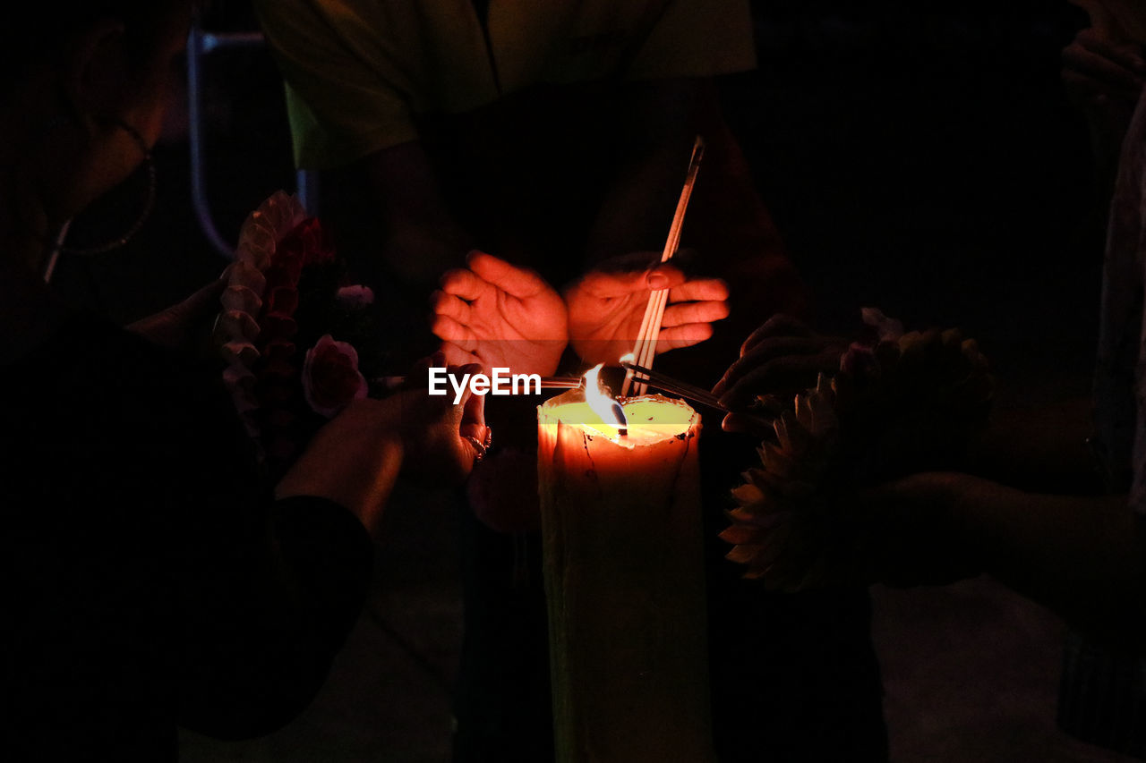 MIDSECTION OF MAN HOLDING ILLUMINATED FIRE