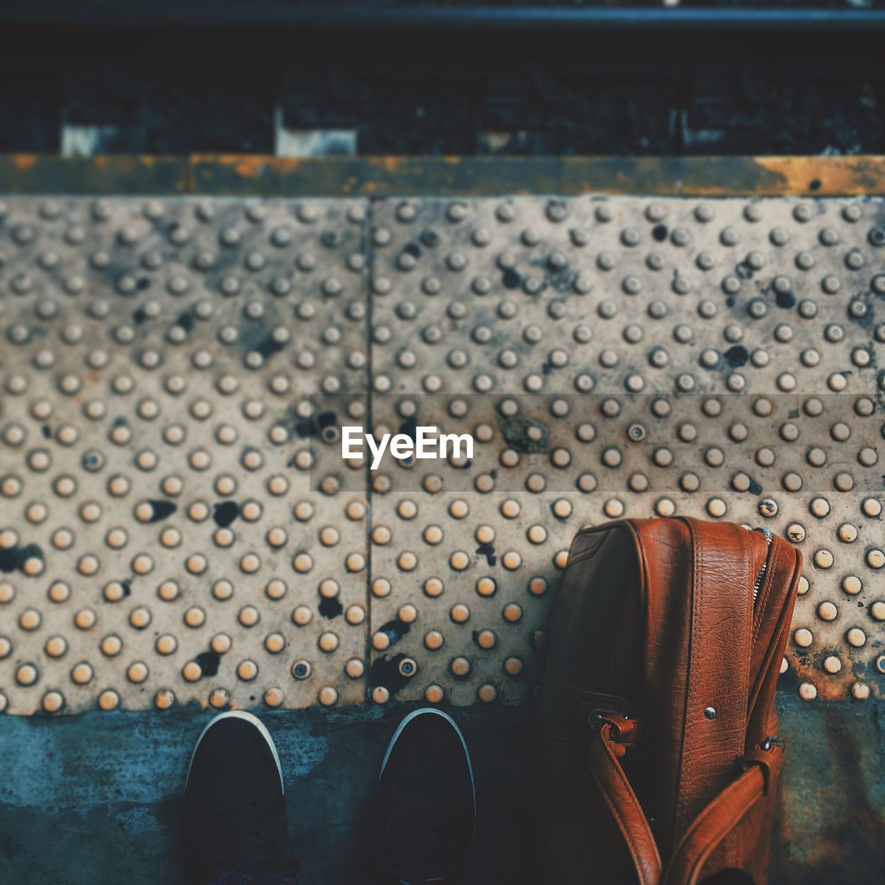 Close-up of cropped shoes and bag on the ground