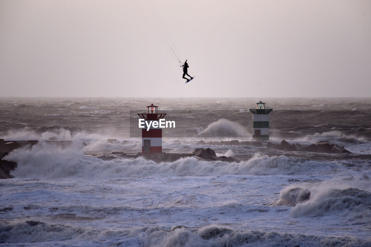 Person kiteboarding on sea against clear sky