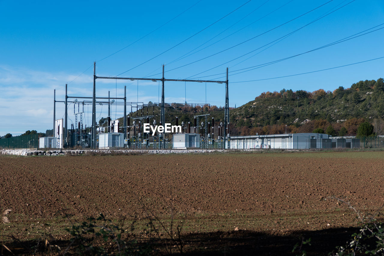 Electrical substation in field against blue sky