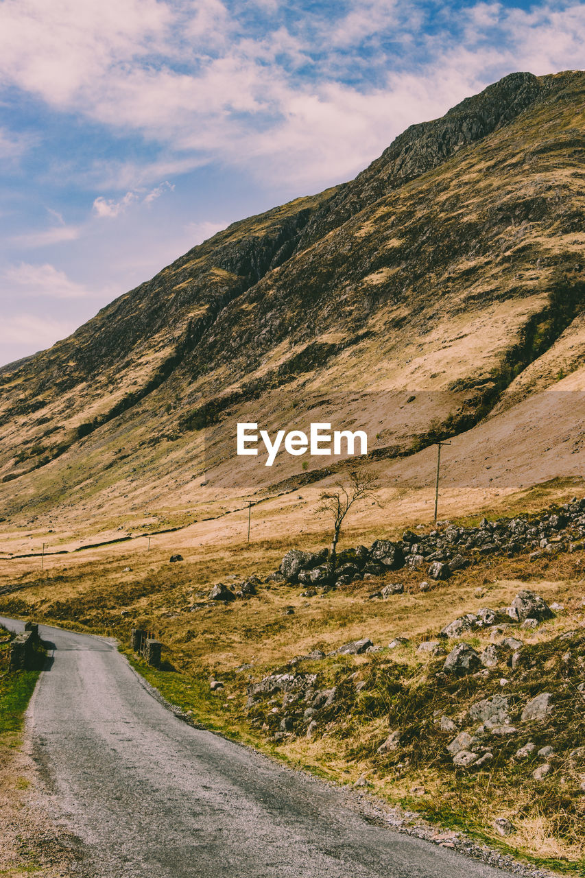 Scenic view of road by mountains against sky