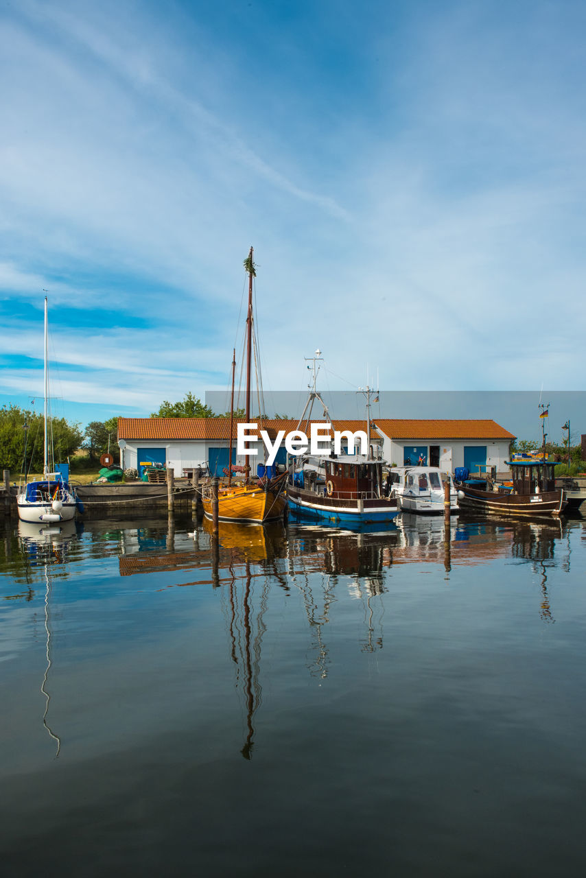 BOATS MOORED IN HARBOR AGAINST SKY