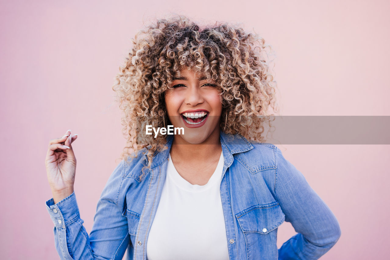 Portrait of smiling hispanic woman with afro hair in city during spring. urban lifestyle