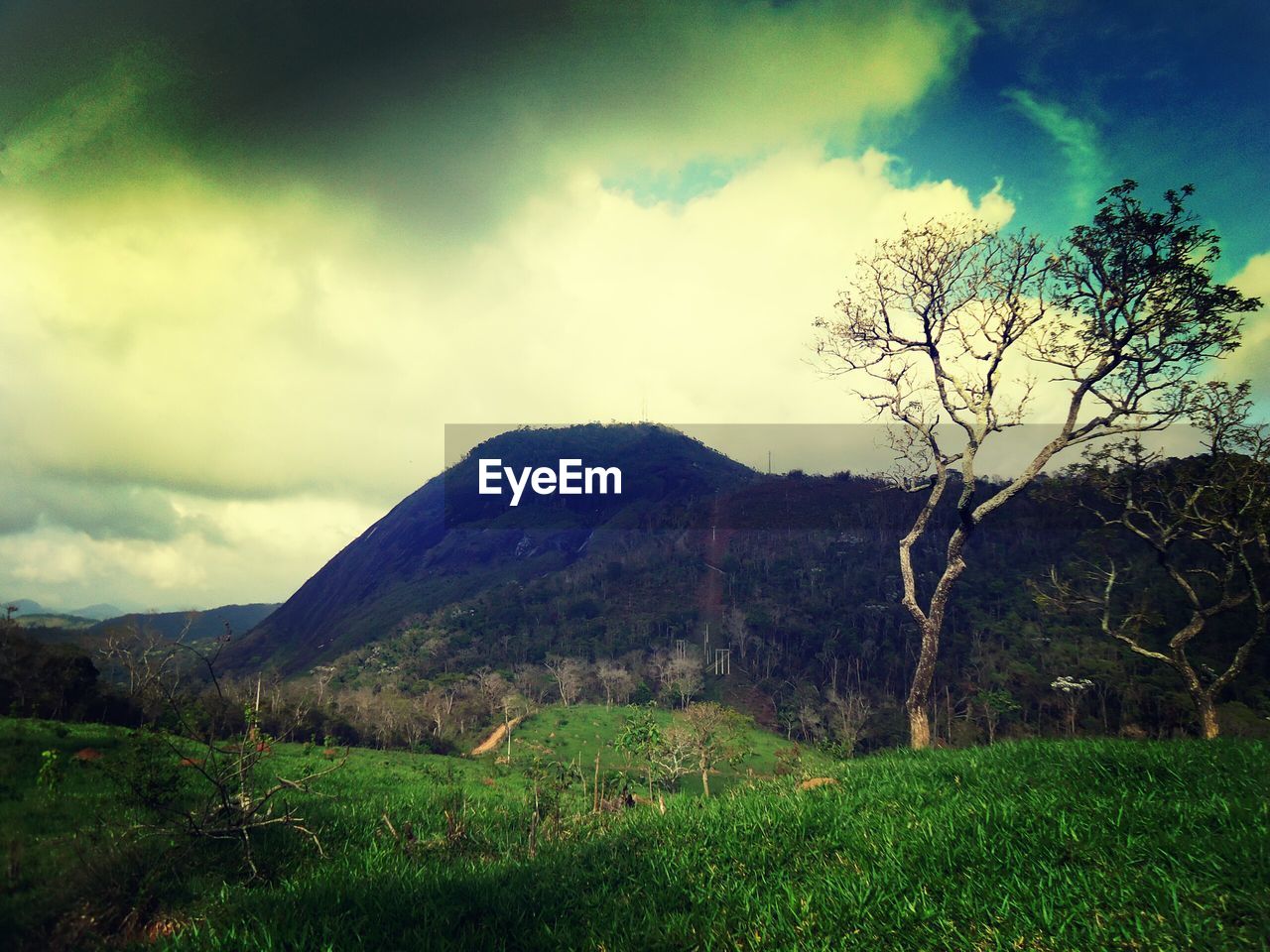 Scenic view of hill against cloudy sky