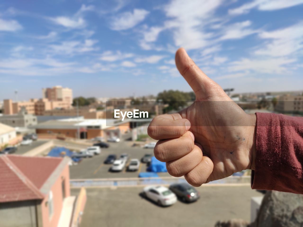 Hand of man holding car against sky in city