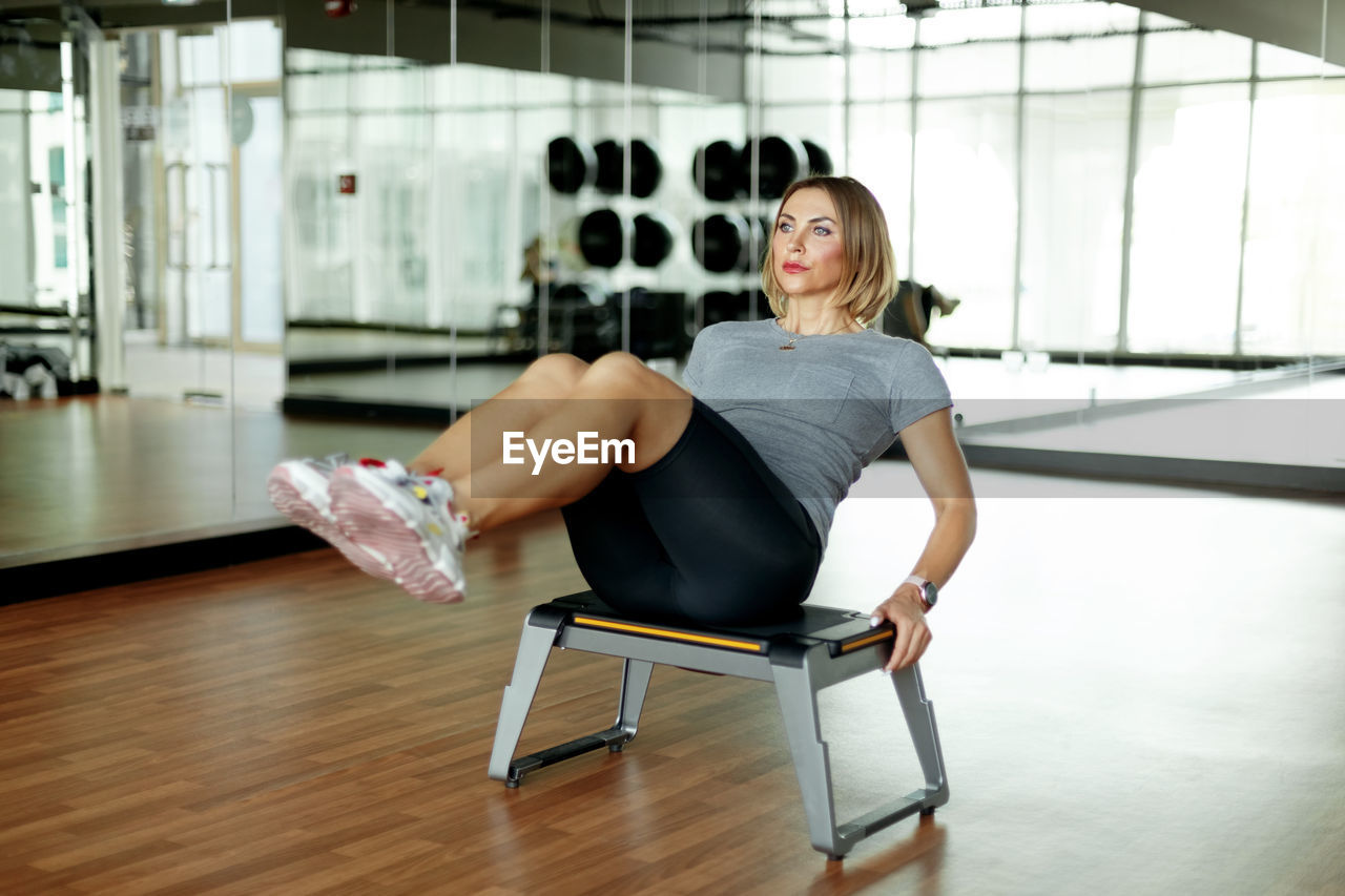 A young woman does abs exercises in the gym on a bench. the concept of sports and a healthy 