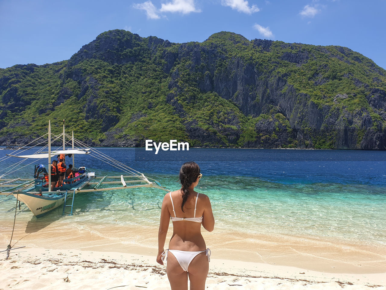 REAR VIEW OF FRIENDS ON BEACH AGAINST MOUNTAINS