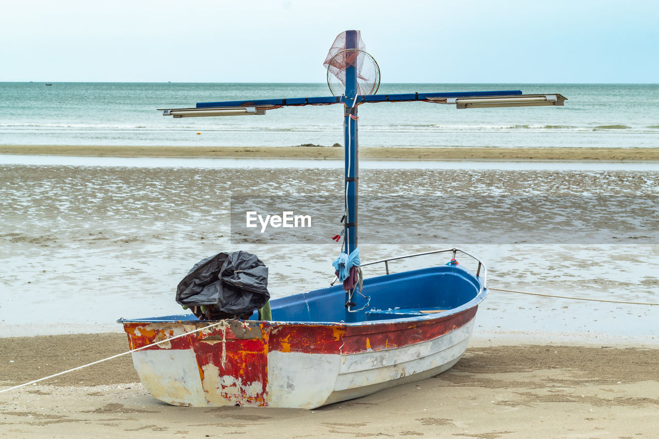 Boat moored at beach against sky