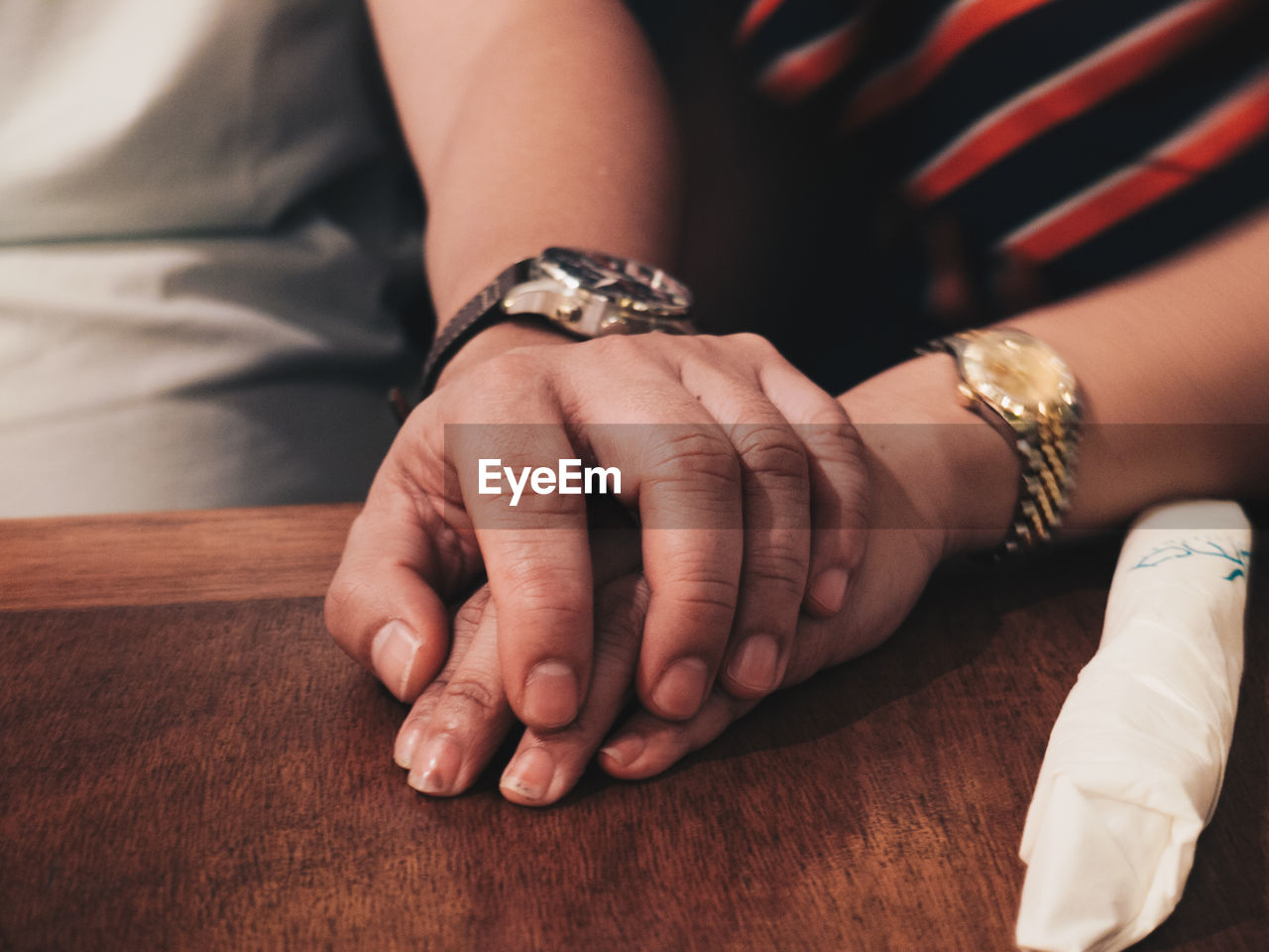 Cropped image of couple holding hands on table