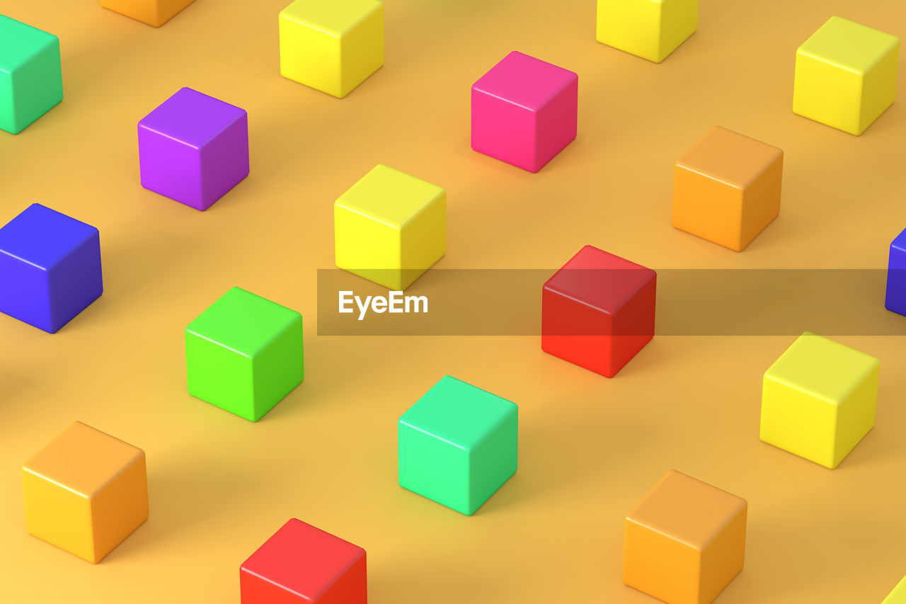 High angle view of multi colored cubes on yellow background