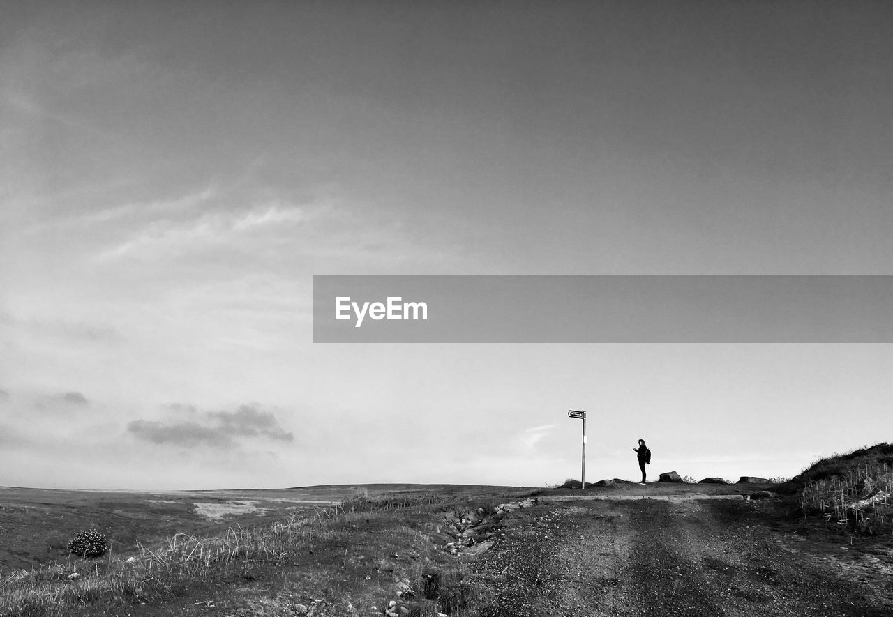 Mid distance view of woman standing on land against sky