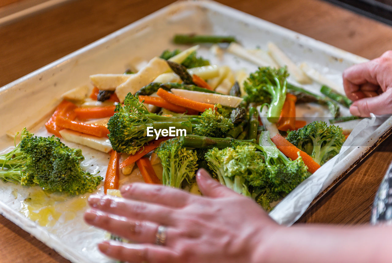 Close-up photo of woman putting mixed vegetables on baking tray