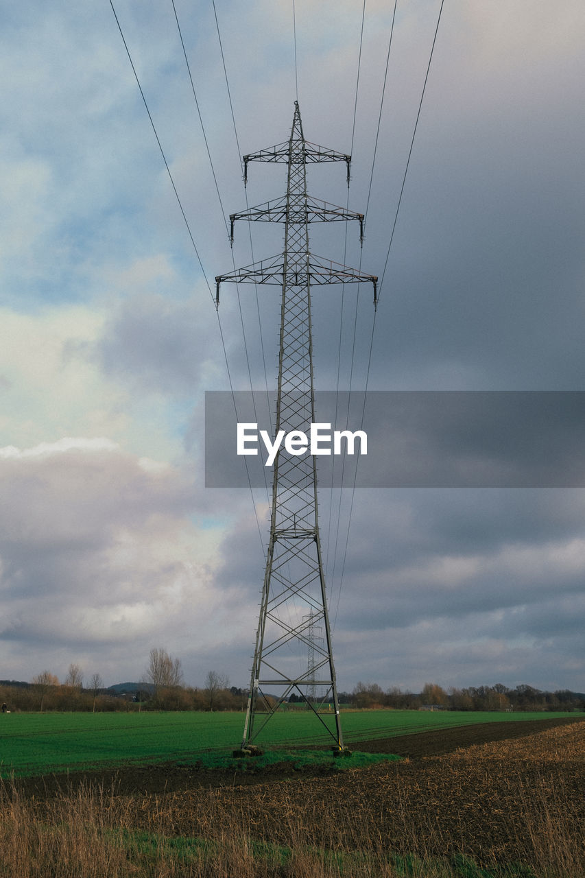cloud, sky, electricity, technology, cable, power generation, electricity pylon, power supply, transmission tower, environment, landscape, nature, overhead power line, tower, land, field, power line, rural scene, agriculture, no people, plant, wind, outdoors, outdoor structure, outdoor power equipment, scenics - nature, grass, day, prairie, architecture, built structure, mast, electrical supply