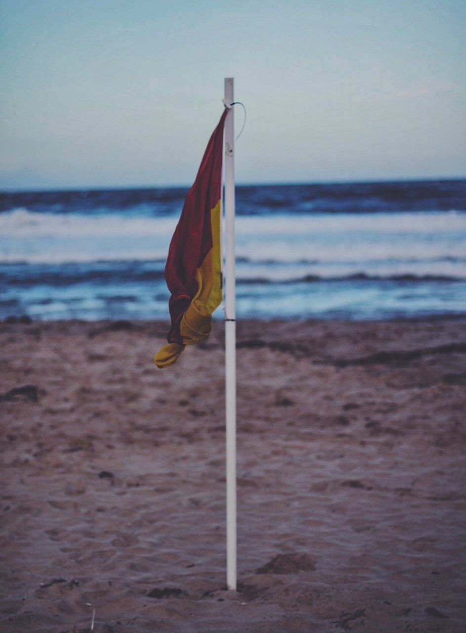 Flag on beach against sky at dusk