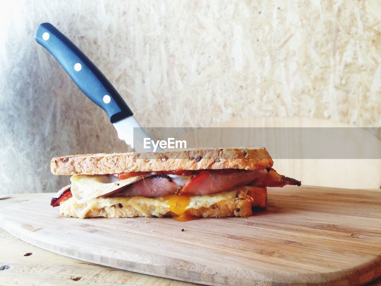 Knife inside sandwich on wooden tray