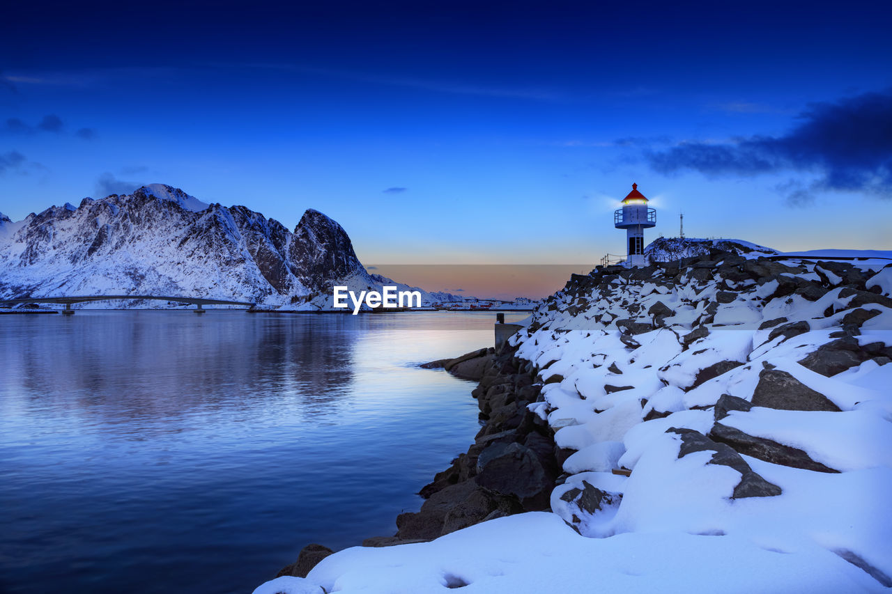 Scenic view of sea and snowcapped mountain against blue sky