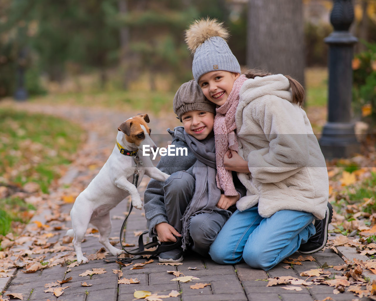 portrait of smiling young woman with dog on field