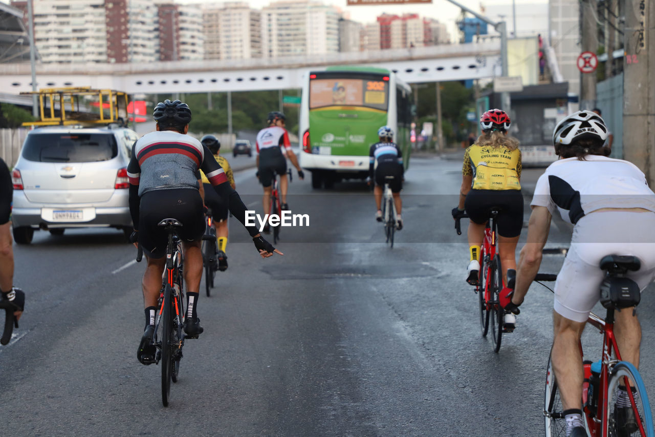 Rear view of people bicycling on road in city