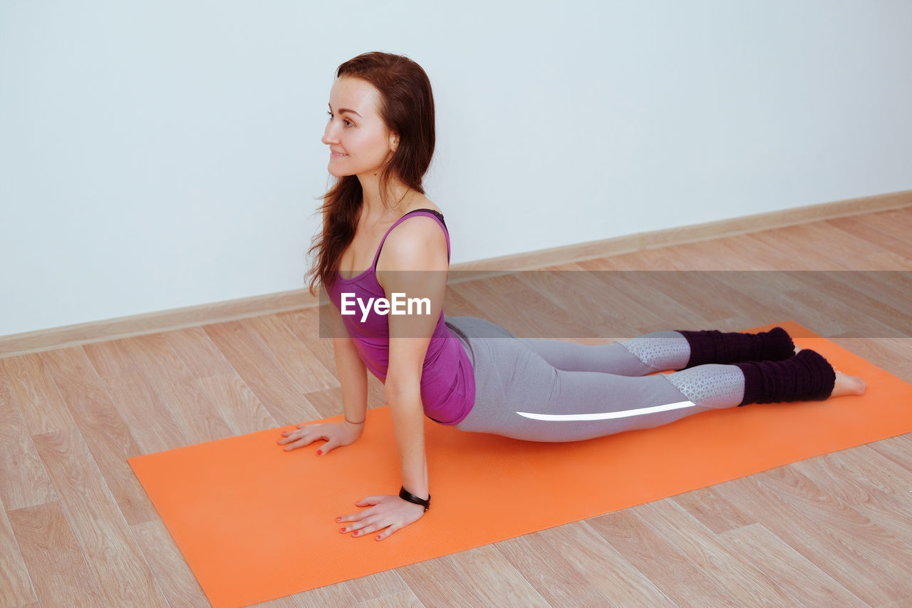 Woman doing yoga exercise on orange mat, stretching.