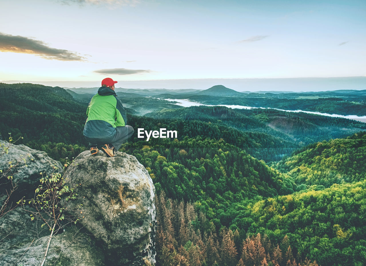 Man stands alone on peak of rock. hiker watching to autumn sun at horizon.  beautiful nascent eday