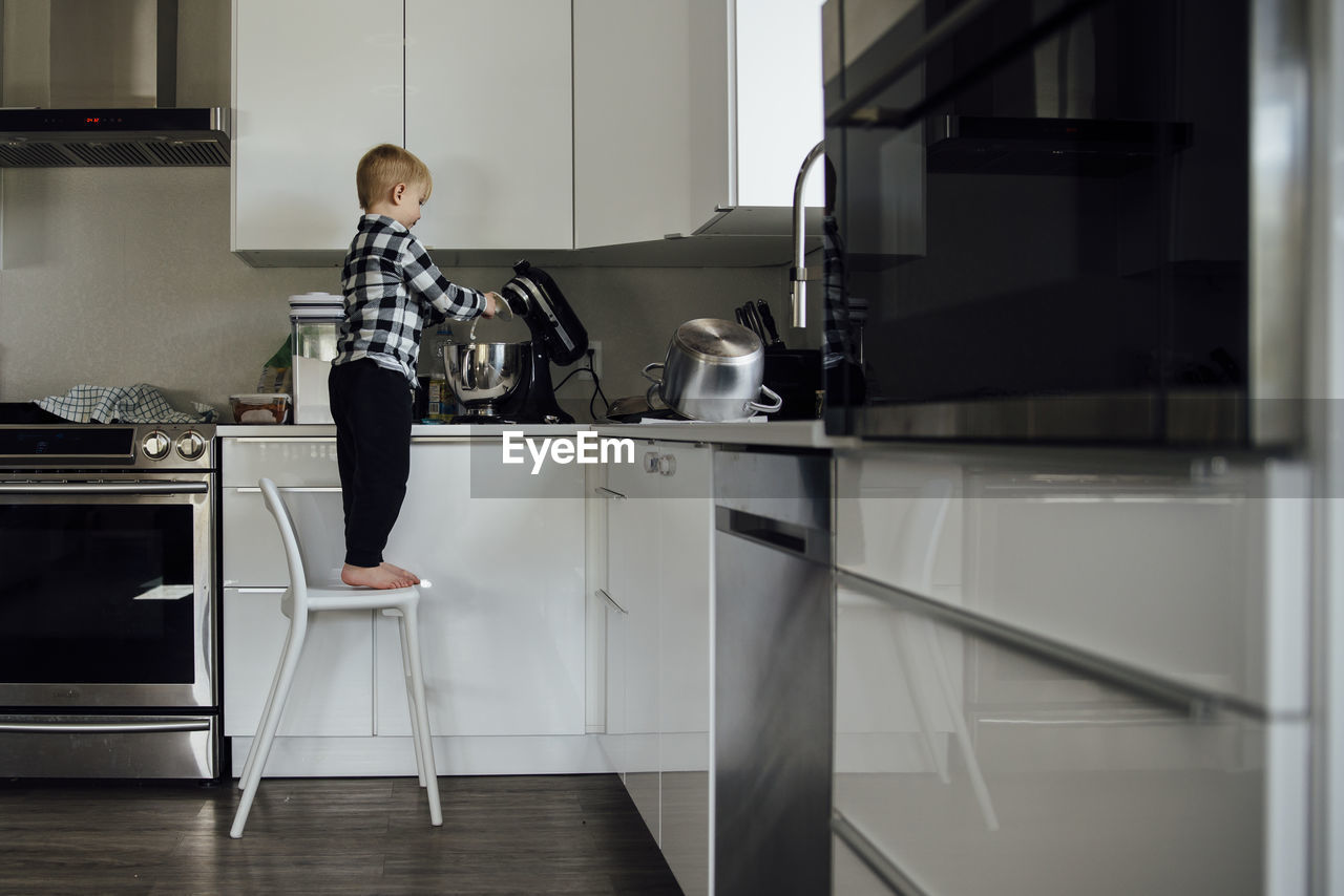 Full length of boy using electric mixer in kitchen