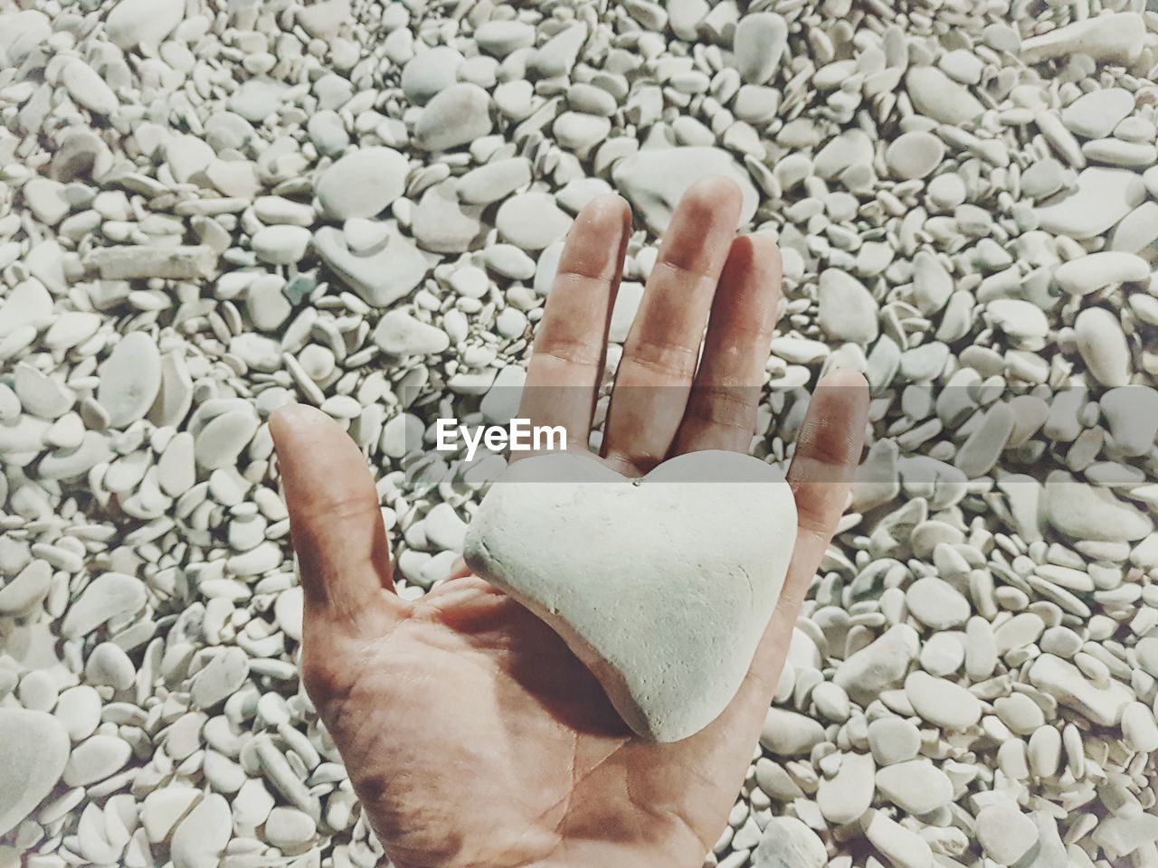Cropped image of person hand on pebbles