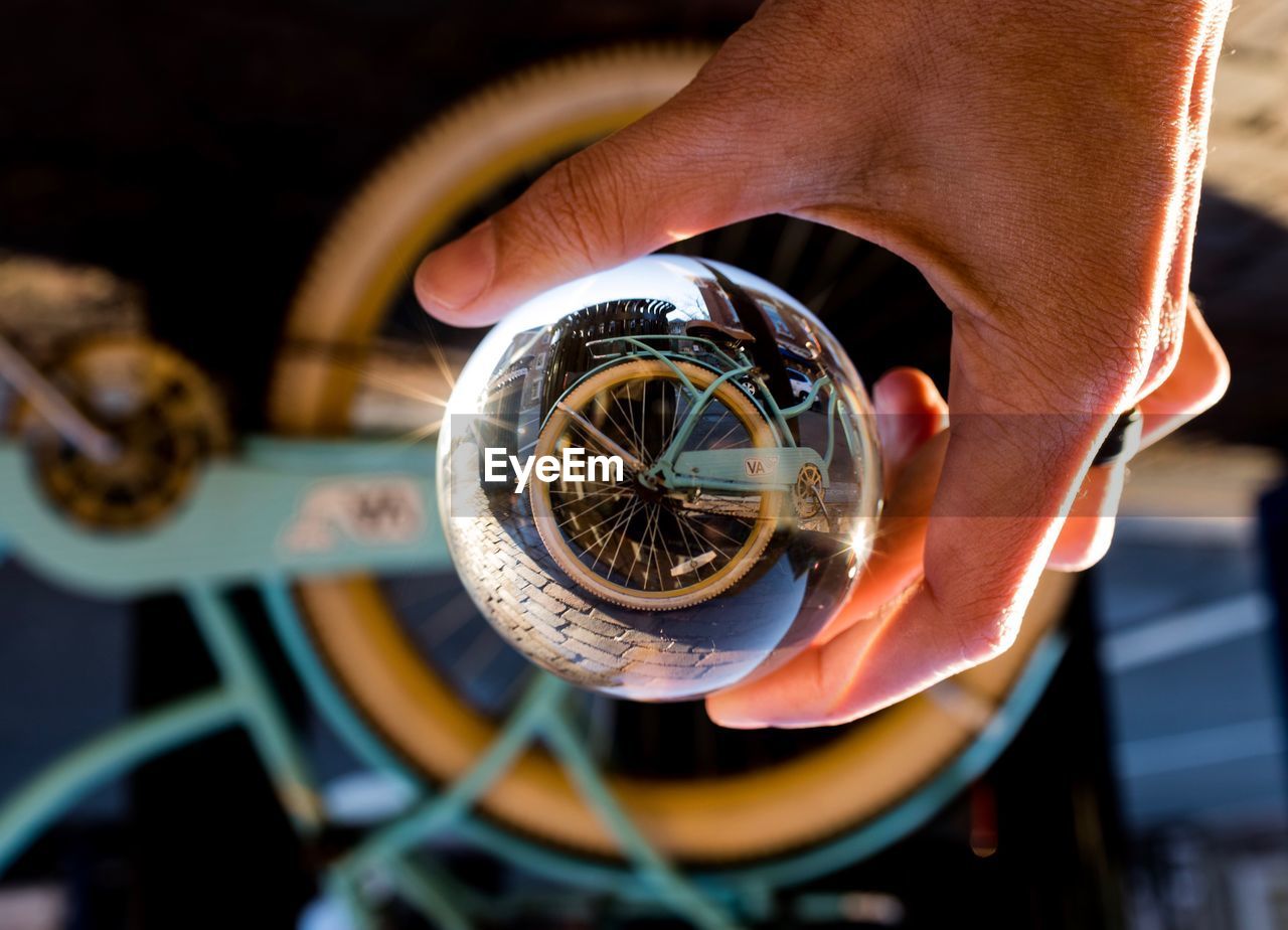 Cropped hand holding crystal ball with bicycle reflection