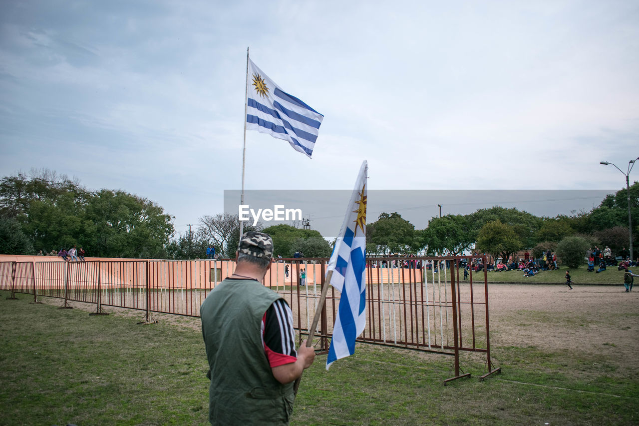 PEOPLE FLAG ON FIELD AGAINST TREES AND SKY