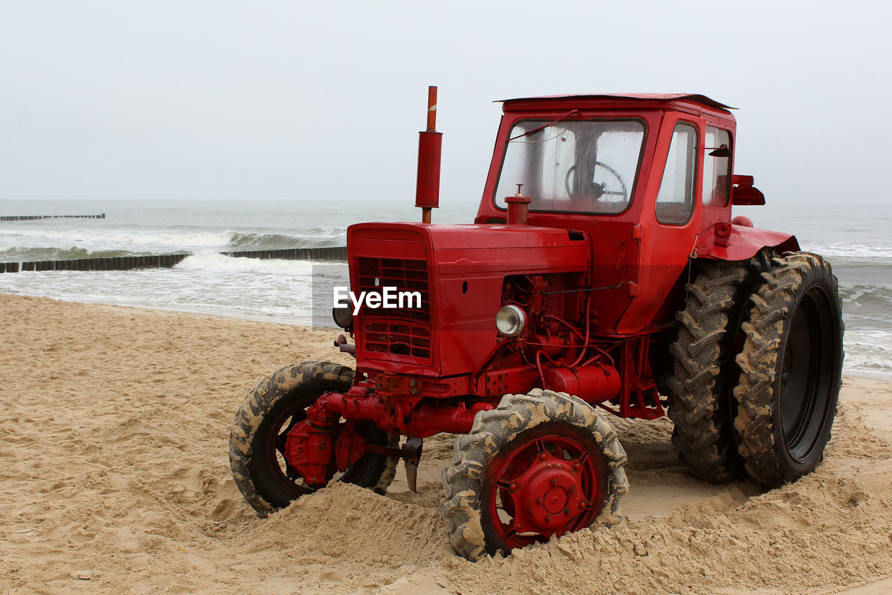 Tractor at beach against clear sky
