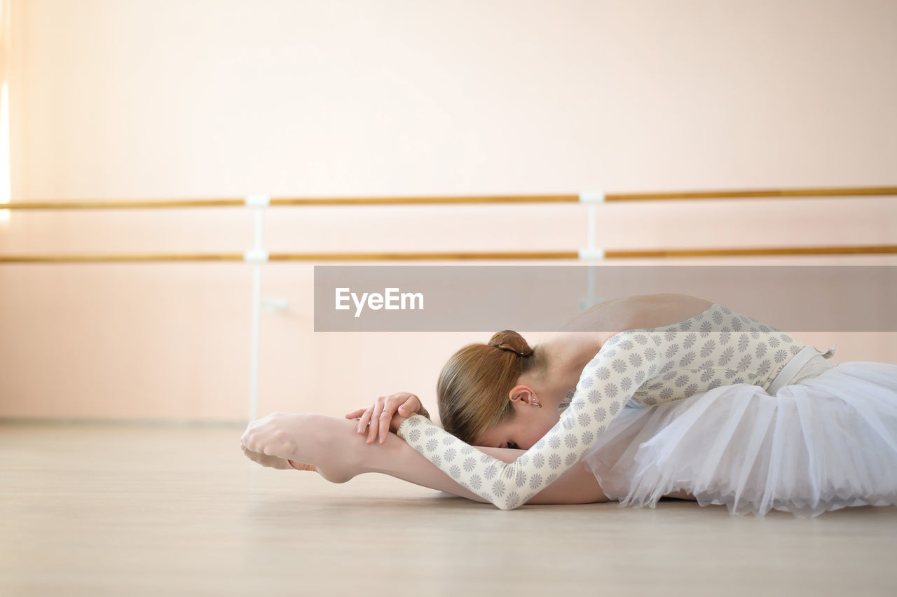 full length of young woman lying on floor at home