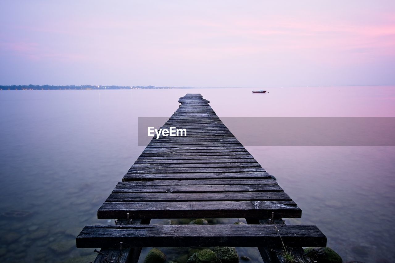 Pier over sea against sky during sunset