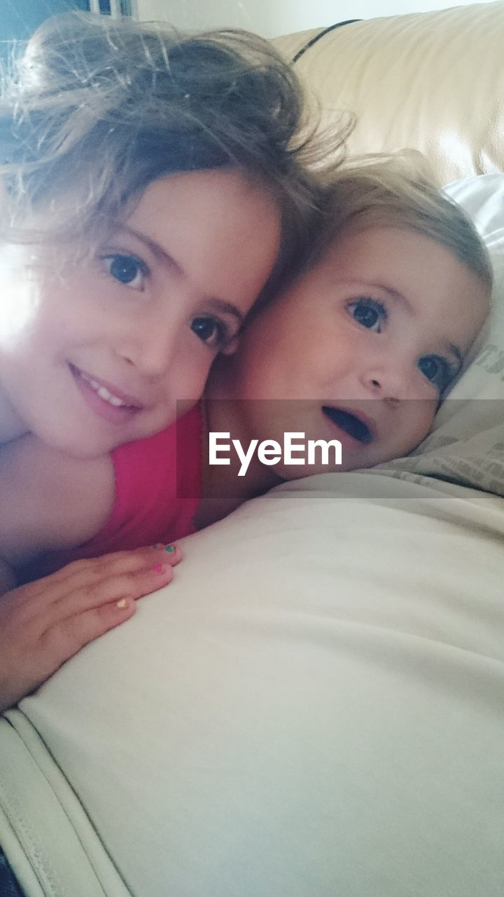 Siblings relaxing on bed at home