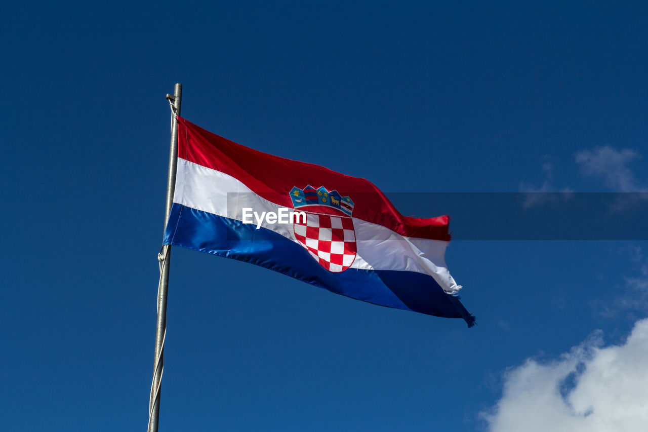 Low angle view of flag waving against blue sky